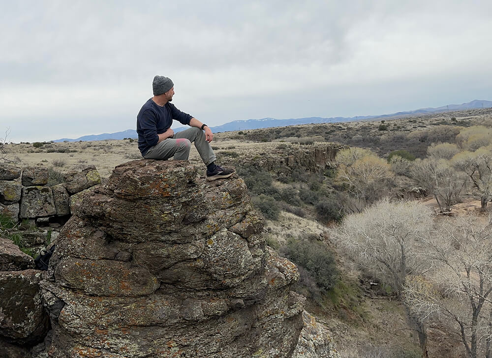 Ivan Fritz sitting on a rock looking at the desert.